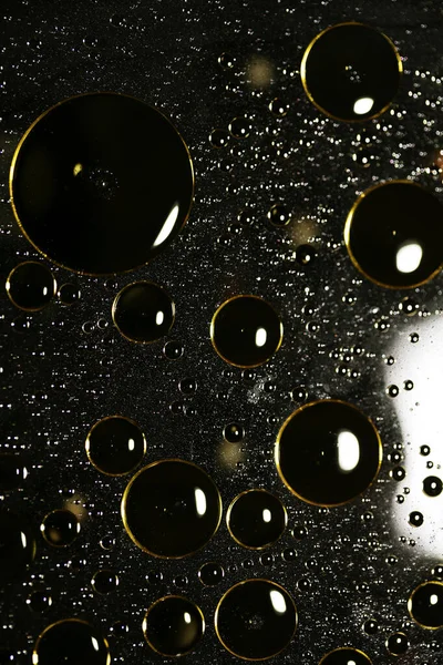 Su siyah zemin üzerinde Bokeh fi ile altın yağ kabarcıkları makro