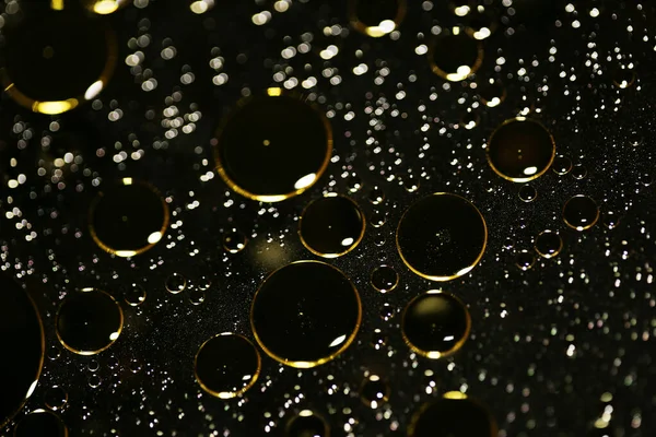 Su siyah zemin üzerinde Bokeh fi ile altın yağ kabarcıkları makro
