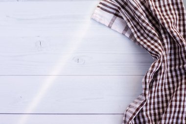 Beyaz kahverengi kareli mutfak havlusu ya da pamuk peçete gri bir ahşap masada yatar. Yukarıdan bak. Uzayı metin için kopyala. Tasarım için bir düzen olarak kullanılabilir. Mutfak arka planı