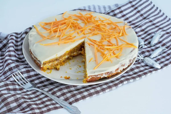 Домашний морковный торт со сливками и белым и коричневым клетчатым полотенцем на белом кухонном столе. Веганский и безглютеновый морковный пирог. Морковный пирог — стоковое фото