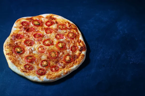 Taze pişmiş ev yapımı pizza siyah ahşap bir masada yatıyor. — Stok fotoğraf