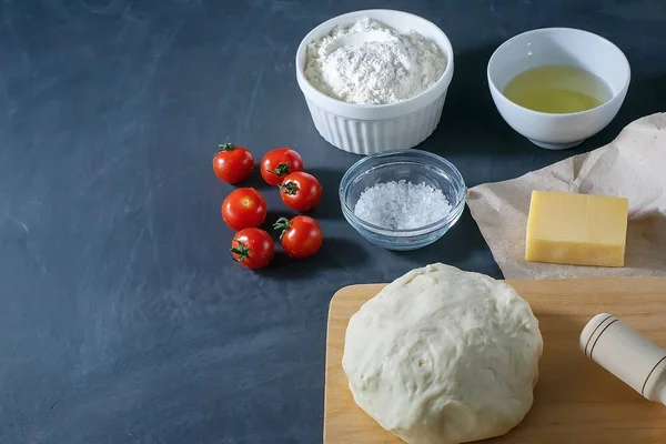 Pizza. Margarita pizza ingredients and raw dough on a black background