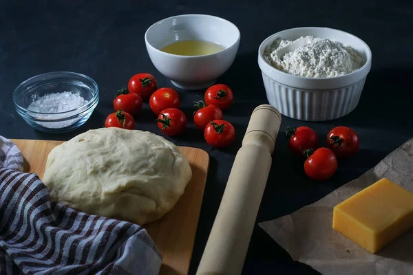 Pizza. Margherita pizza ingredients and raw dough on a black background.