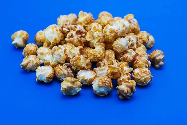 Karamell-Popcorn auf blauem Hintergrund. Filmkonzept. Nahrung zum Filmgucken. Blick von oben. 2020 blaue Hintergrundfarbe — Stockfoto