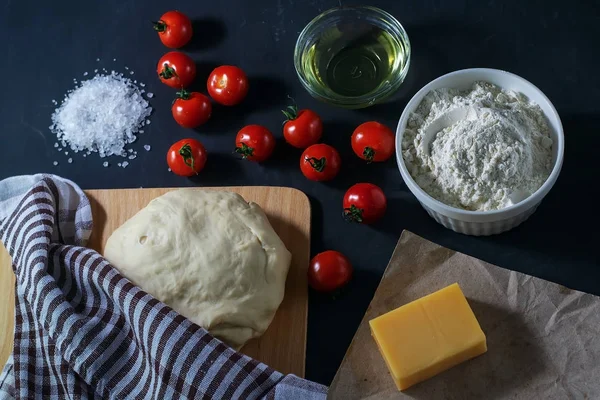 Pizza. Margarita pizza ingredients and raw dough on a black background