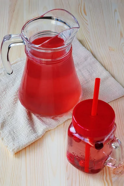 Красный фруктовый сок в кувшине и стеклянная банка на деревянном столе. Концепция здорового питания — стоковое фото