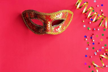 Kırmızı arka planda dekor olan şenlik maskesi. Karnaval kutlaması konsepti, Mardi Gras, Brezilya karnavalı, Venedik karnavalı, karnaval kostümü, bahar. Düz konum, üst görünüm, metin için yer