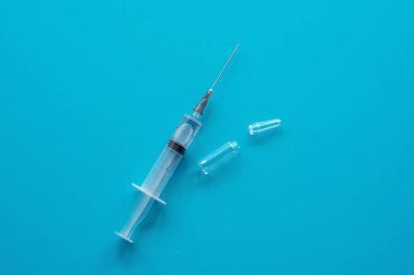 Enjeksiyon için şırınga ve mavi arka planda ampul. Tıp konsepti, sağlık hizmeti. Düz yat, boşluğu kopyala