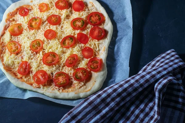 Rohe Pizza Liegt Auf Einem Backpapier Auf Schwarzem Hintergrund lizenzfreie Stockfotos
