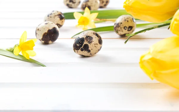 复活节彩蛋和木制的桌子上的花 在板材上春天概念 图库图片