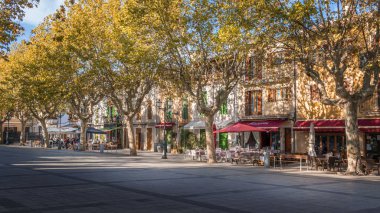 Arta şehir meydanı (Placa). Sonbaharda tipik İspanyol kasabasının merkezi. Autmn ağaçlarının arkasındaki restoranlar, kafeler ve dükkanlar, Arta, Mallorca, İspanya