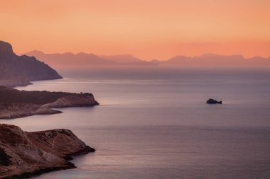 Cala Mesquida, uzak bir tepeden Akdeniz ve günbatımında uzak yarımadaları görüntüledi.