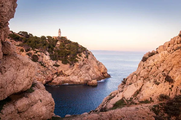 Farol Capdepera, pôr do sol com luz suave, baía com rochas e árvores, Cala Ratjada, Maiorca, Espanha . — Fotografia de Stock