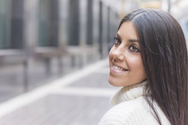 Modern ve gülümseyen genç kız sokakta poz veriyor.