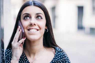 Modern ve gülümseyen genç kız cep telefonuyla konuşuyor.