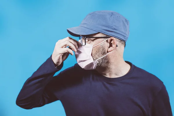 Portrait of man with face mask and cap with a blue background. Concepts of contagion, influenza or coronavirus