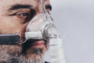 Uyku bozuklukları için solunum maskesi takan yaşlı bir adam. Apne. Tıbbi cihazlar. Hava pompası. Solunum desteği. Boşluğu kopyala