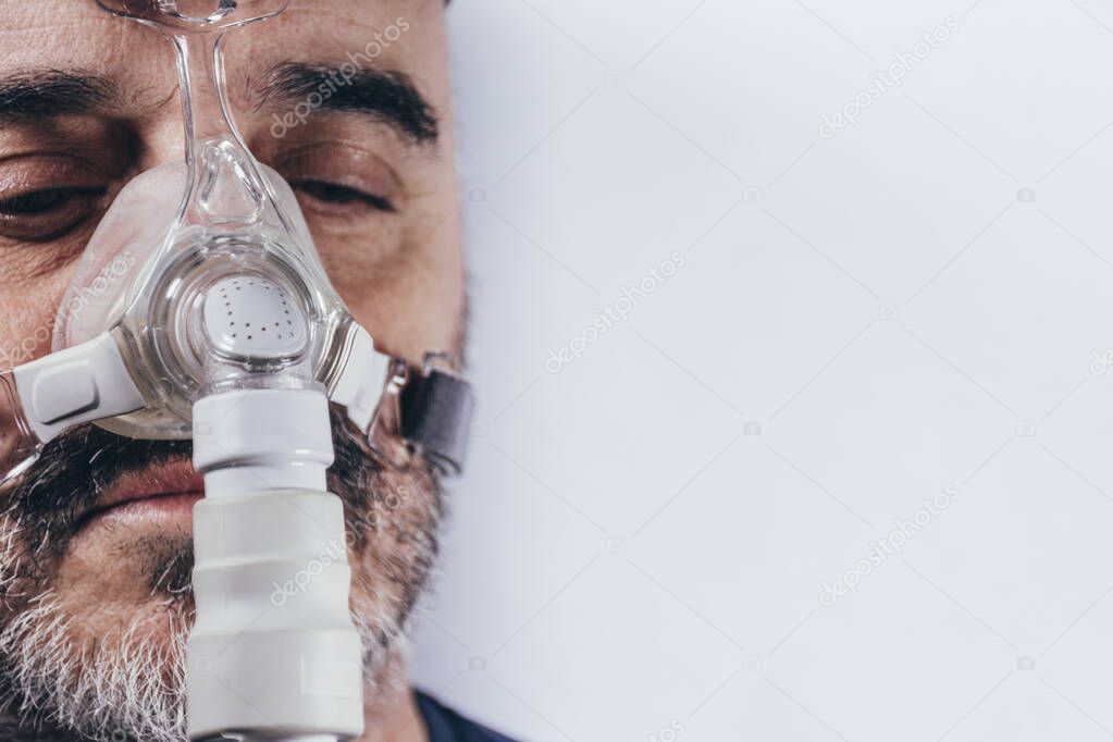 Senior man with respiratory mask for sleep disorders. Apnea. Medical devices. Air pump. Assisted breathing. Copy space