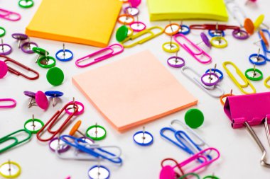 Ofis için parlak pembe, sarı, mavi ve yeşil kırtasiye aksesuarları ve beyaz arka planda eğitim için yapışkan notlarla kopyalama alanı.