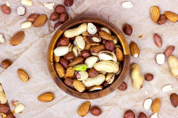 Farklı fındıkların üst görüntüsü: badem, fıstık, fıstık, fındık, ahşap kasede hafif arka planda..