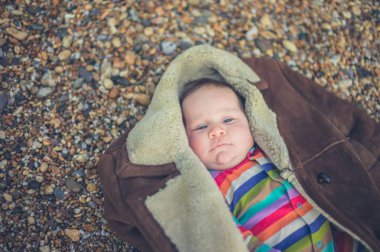 Küçük bir bebek sahilde paltolu sarılmış