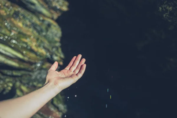 一个年轻女子的手正在洞穴中捕捉水滴 — 图库照片