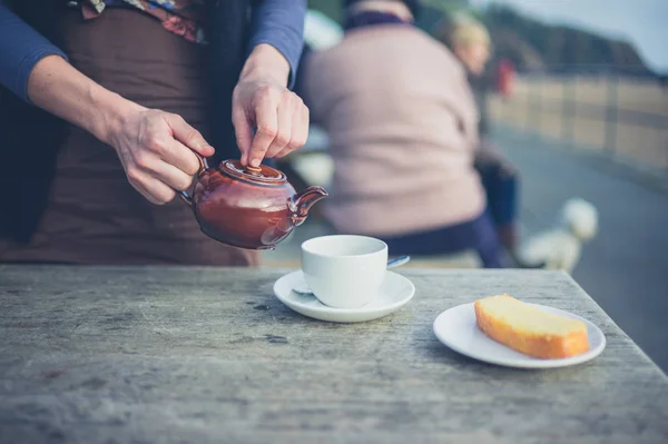 外のテーブルでお茶を注ぐ女性 — ストック写真