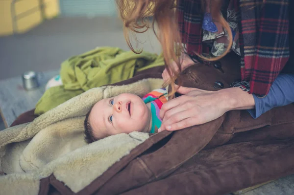 Mor inslagning baby i coat utanför — Stockfoto
