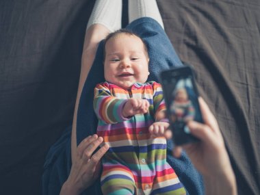 Mother taking photo of her baby clipart