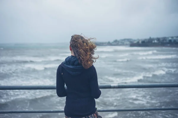 Junge Frau an stürmischem Tag am Meer — Stockfoto