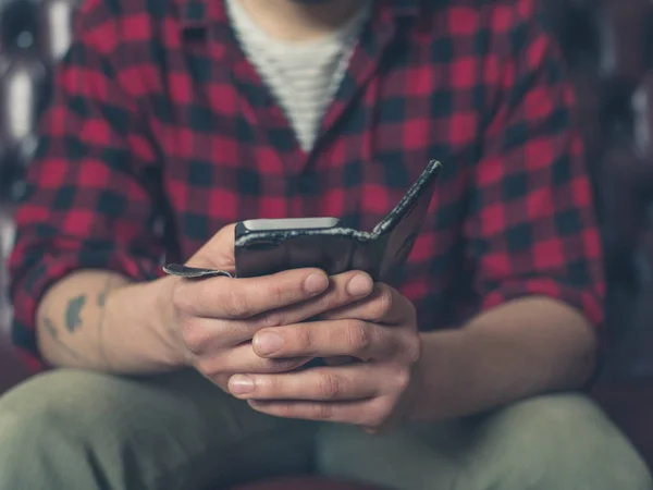 Молодой человек на диване с помощью смартфона — стоковое фото