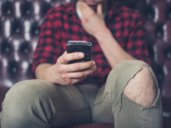 Junger Mann auf Sofa mit Smartphone — Stockfoto