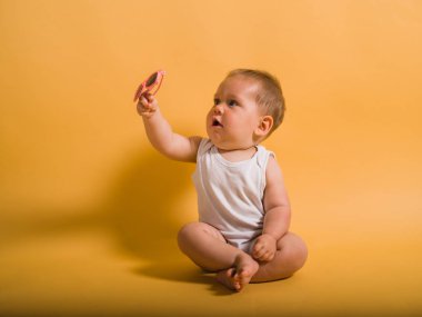Sarı arka planı güneş gözlüğü ile oturan bir şirin bebek