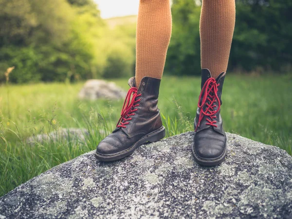 一个穿着靴子的年轻女子的脚站在自然岩石上 — 图库照片