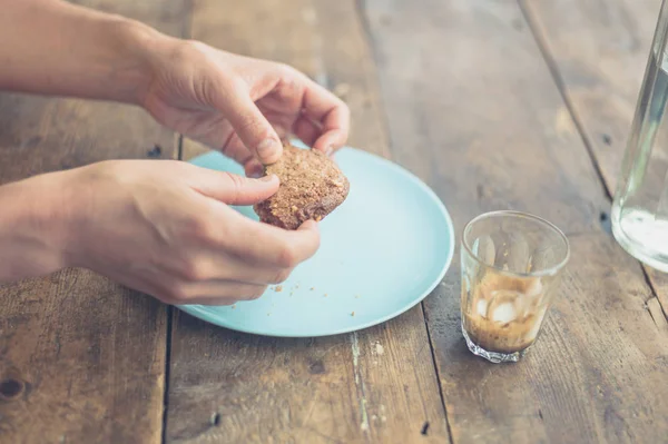Mladá žena jíst cookie v kavárně — Stock fotografie