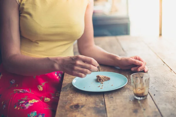 Jonge vrouw cookie eten in café — Stockfoto