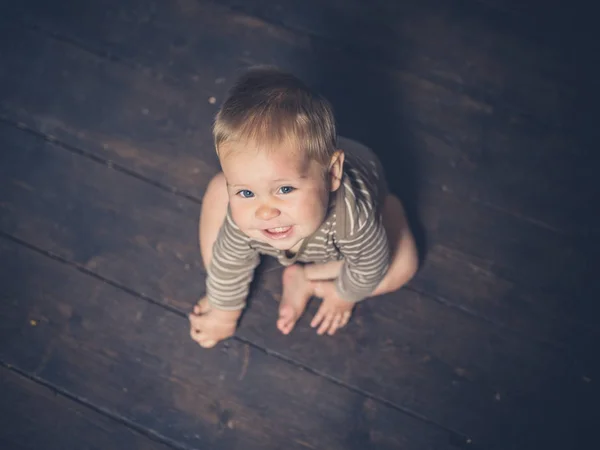 Piccolo bambino seduto su assi del pavimento — Foto Stock