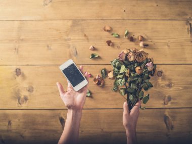 Kırık akıllı telefon ve ölü çiçekler kadın ile