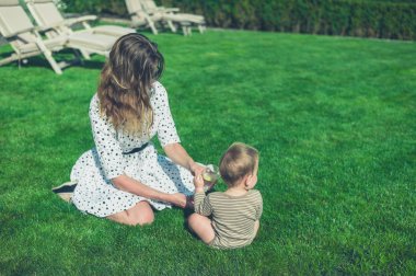 Anne ile bebeği güneşin çimenlikte oturan