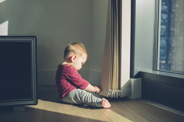 Маленький ребенок сидит у окна — стоковое фото