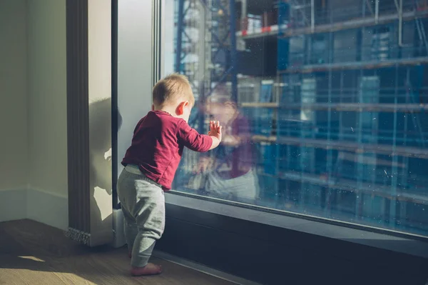 Маленька дитина стоїть біля вікна — стокове фото