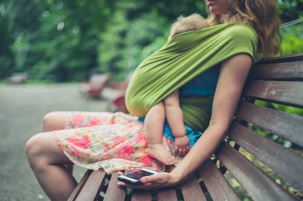 Matka z dzieckiem w parku przy użyciu smartfona — Zdjęcie stockowe
