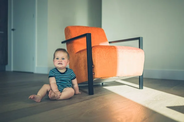 Niedliches kleines Baby sitzt auf einem Stuhl im Sonnenlicht — Stockfoto