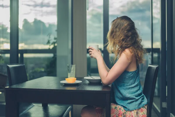 Mujer joven desayunando junto a la ventana de la ciudad — Foto de Stock