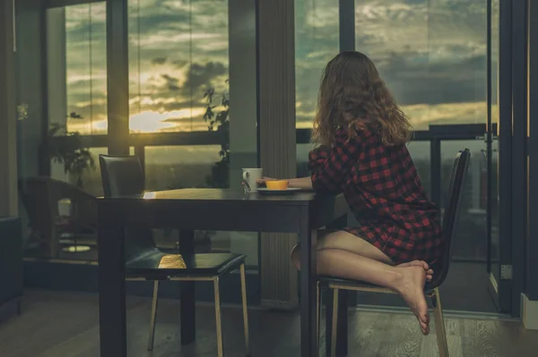 Mujer desayunando por ventana en el apartamento de la ciudad —  Fotos de Stock