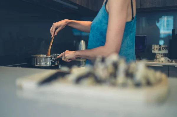 Genç bir kadın mutfakta yemek pişiriyor. — Stok fotoğraf