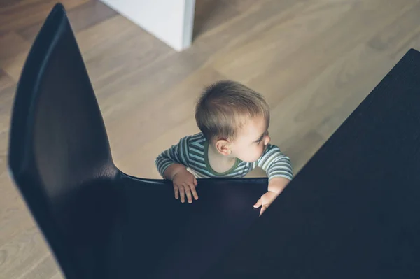 Lilla bebis stående av stol och bord — Stockfoto