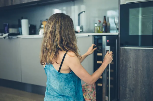 Mulher recebendo garrafa de vinho de refrigerador — Fotografia de Stock