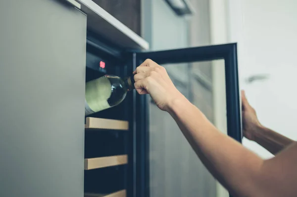 Женщина получает бутылку вина из холодильника — стоковое фото