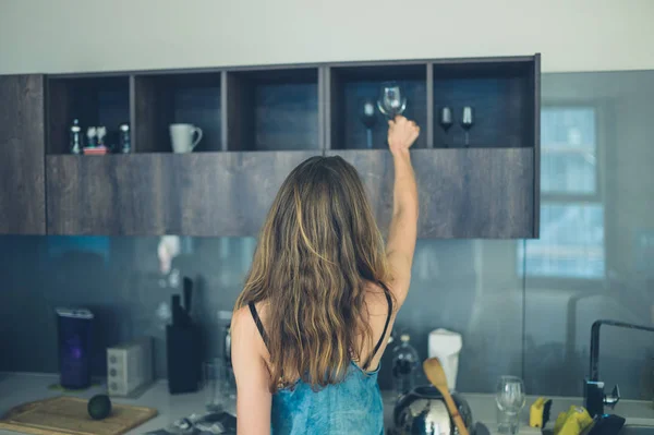 Young woman getting wine glass in kitchen — Stock Photo, Image